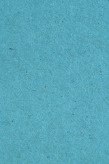 The surface of light blue cardboard. Rough natural paper texture with cellulose fibers. Background or wallpaper. Top view from above. Vertical shot. Macro