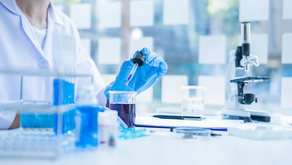 Fototapeta premium Medical or scientific researcher or man doctor looking at a test tube of clear solution in a laboratory