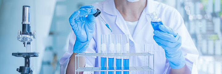 Medical or scientific researcher or man doctor looking at a test tube of clear solution in a...