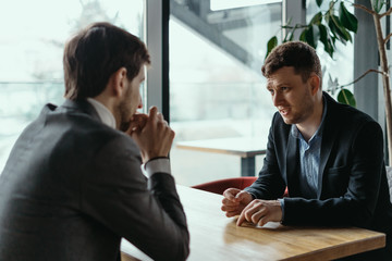 Focused businessman listening to business partner talking during discussion, thinking over his...