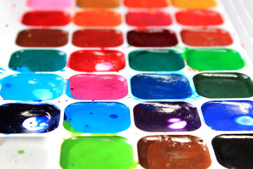 Close-up dirty set of multicolored watercolor paints