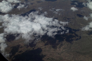 View of the mountains from the plane. Beautiful mountain landscape. Mountains surrounded by clouds. Wallpaper and background.