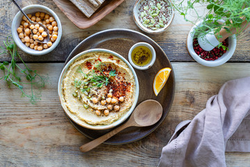 Hummus, chickpea sauce with smoked paprika olive oil in a ceramic bowl on a wooden background. Top view.
