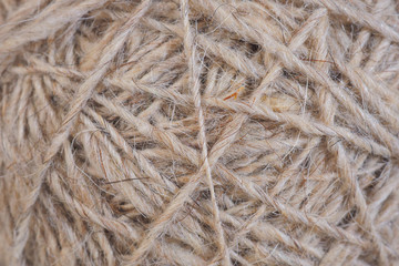 Ball of natural unpainted wool handmade closeup. Light brown or beige background or wallpaper. Handicraft, knitting and hobbies. Macro strings, filaments and threads