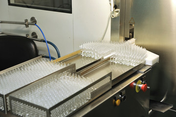 Visual control of ampoules with medicine. A woman works on an ampoule production line. Sterile bottles and ampoules on the dispensing line. Sealed ampoules with medicine. Sterile capsules for