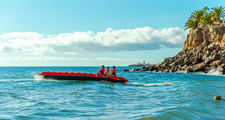 Beach sports and relaxation. People ride the sea on an inflatable banana. Gran Canaria