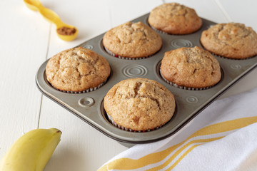 Tray of Banana Nut Muffins with Banana, Kitchen Towel and Cinnamon