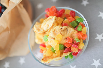 Multicolored candied fruits in a transparent stylish jar on the table.