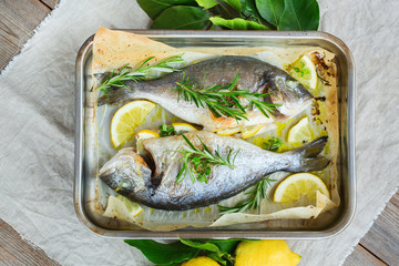 Fresh grilled roasted dorado fish with lemon, rosemary on table