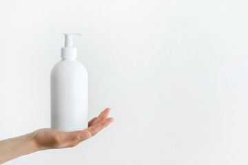 Woman hand holding dispenser with antiseptic. Hygiene prevention of coronavirus and infection. Sanitizer in white plastic bottle.