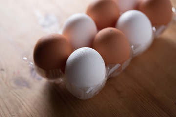 A carton of mixed brown and white eggs on a wooden background.