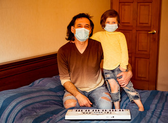 father and daughter, in medical masks, sit at home in quarantine, because of the covid-19 pandemic,...