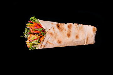 Delicious turkish doner kebab with chicken grilled, onion, tomatoes, lettuce, parsley, carrot,  cucumbers and sauce isolated on black background 