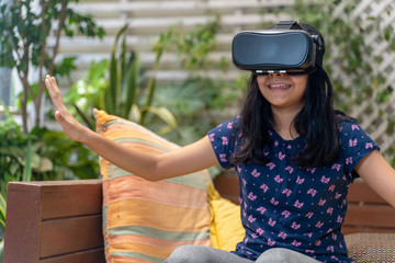 Fototapeta premium Indian Asian girl viewing through a Virtual Reality device, experiencing immersive technology