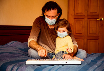 father and daughter, in medical masks, sit at home in quarantine, because of the covid-19 pandemic,...