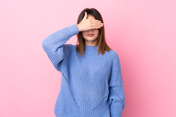 Young woman with blue sweater over isolated pink background covering eyes by hands