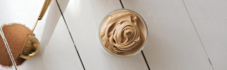 Iced frothy Dalgona Coffee, a trendy fluffy creamy whipped coffee. Korean drink latte espresso with coffee foam. made of instant coffee, sugar, hot water and milk. banner with copyspace.