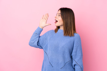 Young woman with blue sweater over isolated pink background shouting with mouth wide open