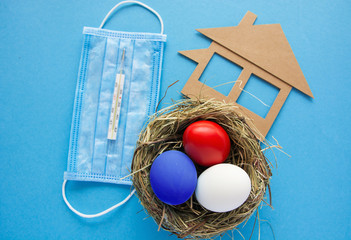 Easter eggs colored red, blue,white in the nest with protective face mask, house and thermometer -...