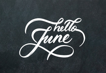 "Hello June" hand lettering inscription on black chalkboard background.