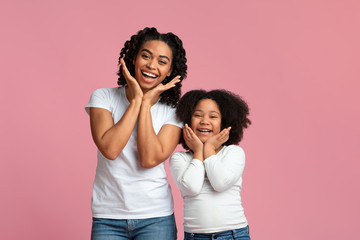 Naklejka premium Cheerful black mom and daughter having fun together, making funny poses