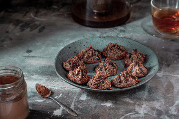 Homemade coconut cookies with cocoa, on a gray plate and shabby wooden background. Dark food photo.