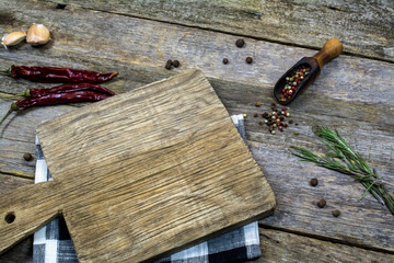 The cutting board lies on an old table next to dry red pepper and seasonings.