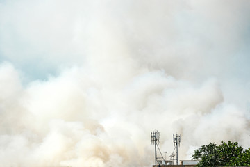 accident fire and white smoke overview in city blowing on blue sky. emergency danger air pollution in summer season.