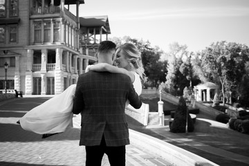 The groom holds the bride in his arms at the wedding, happy newlyweds