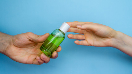 coronavirus prevent green sanitizer on a blue background in a male hand is transmitted to a female...