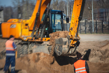 Yellow heavy excavator excavating sand and working during road works, unloading sand during...