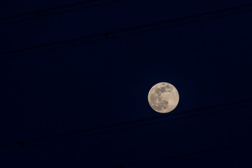 The beautiful super moon of April 7, 2020 seen through the high voltage wires against the blue sky...