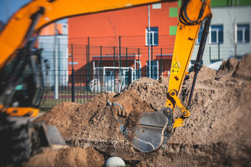 Yellow heavy excavator excavating sand and working during road works, unloading sand during...