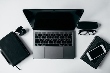 Freelancer workplace on a white background with place for text. View from above. Laptop, glasses, cup, notebook, pen, phone and headphones