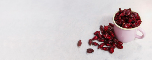 Dried rose hips in enameled mug top view on white background
