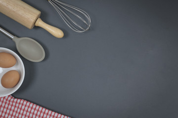 Wooden dough roller and whisk on the black table.