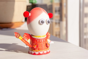 Naklejka premium Egg for easter day. Egg is girl in the orange dress with eyes. Background close up. Easters celebration concept. Background horizontal format