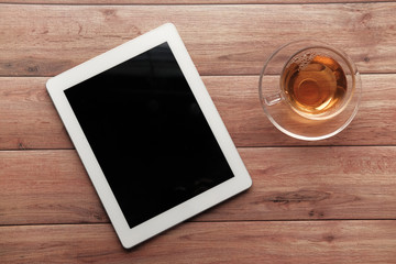 top view of digital tablet and tea on wooden table 