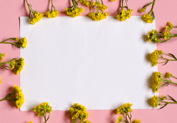 Frame of flowers. White piece of paper sheet on a pink background. Place for your text. Floral background.