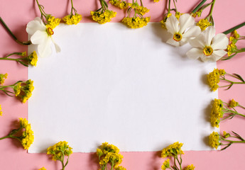 Frame of flowers. White piece of paper sheet on a pink background. Place for your text. Floral background.