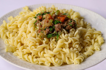 Turkish style ground beef, tomato, onion and parsley pasta in a white plate.