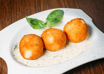 Beef Arancini on restaurant table with 4 cheese sauce