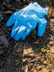 Blue disposable protective latex glove lying on the ground