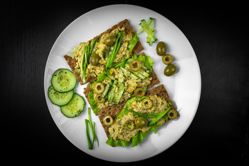 Healthy sandwiches with avocado, hummus, cucumber on  white plate, top view. 