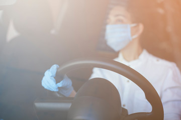 Woman in surgical face mask and gloves driving car