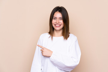 Fototapeta premium Young woman over isolated background pointing finger to the side