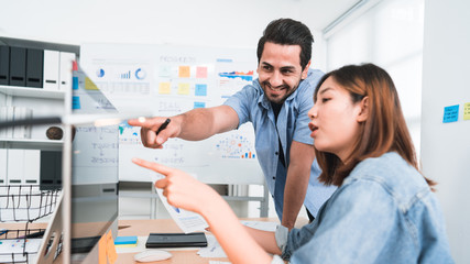 Obraz premium Happy and relaxed office workers point out new ideas or solutions casually toward computer on the office desk, the concept of teamwork, working lifestyle, positive healthy working, creative strategy.