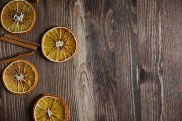 Orange chips with cinnamon close up on a brown wooden background with copy space