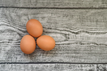 Three chicken brown eggs on the wooden background.