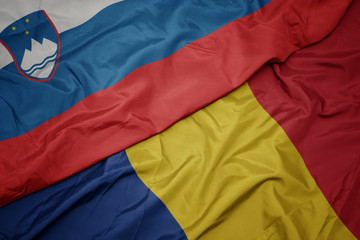 waving colorful flag of romania and national flag of slovenia